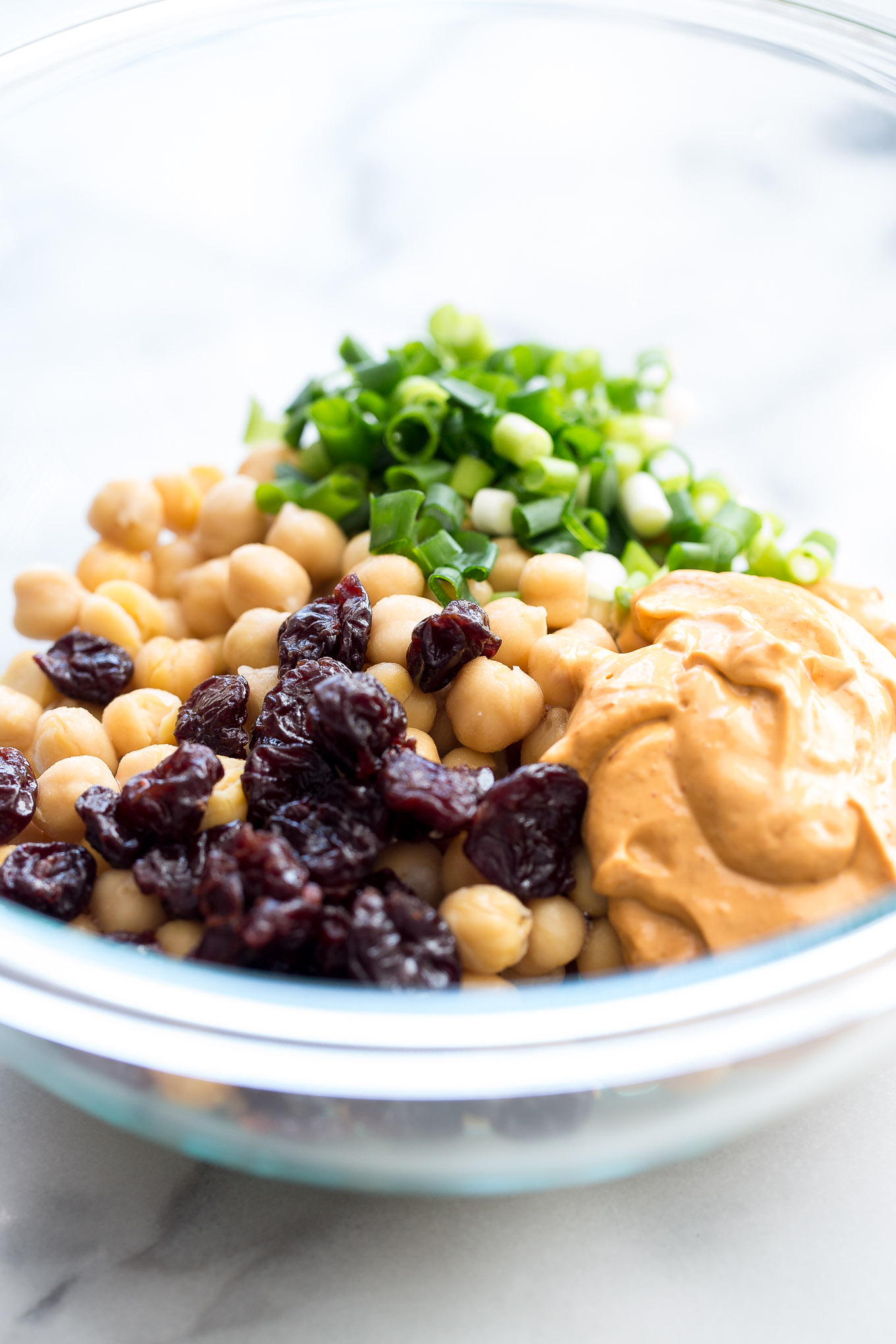 Healthy chipotle chickpea salad. Made with delicious real food with only 5 ingredients. Chickpeas, green onions, chipotle vegenaise, red pepper flakes, dried cherries and sea salt. Vegan. tasteofyummy.com