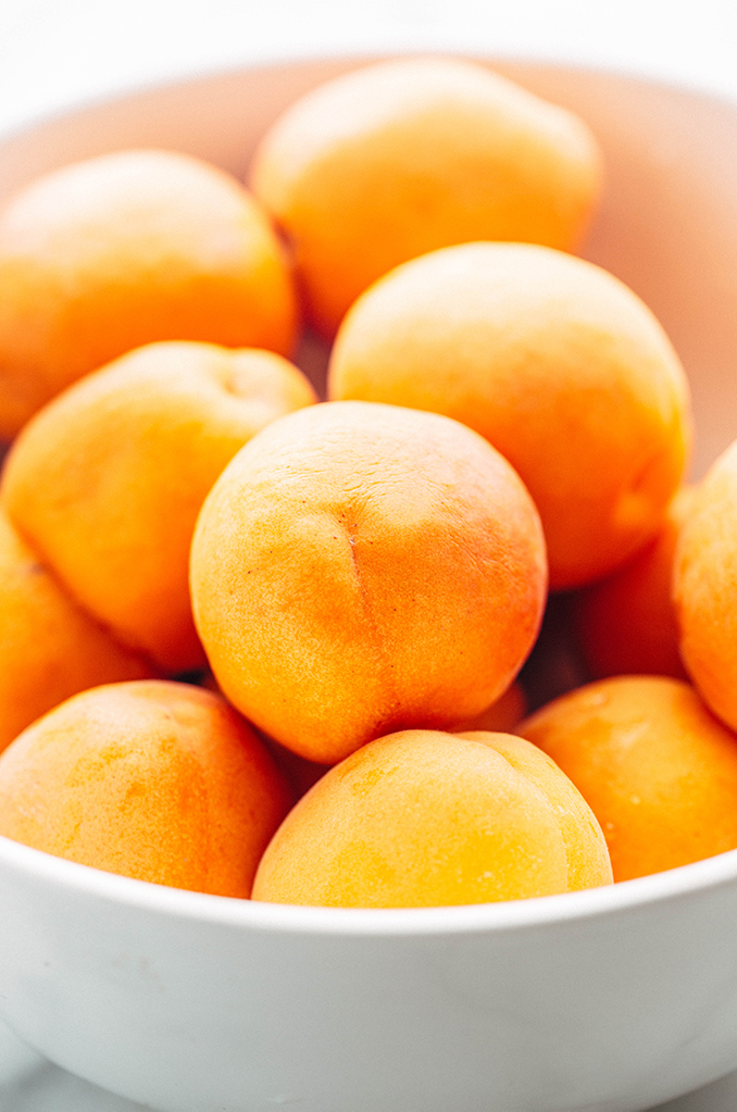 a white bowl of apricots