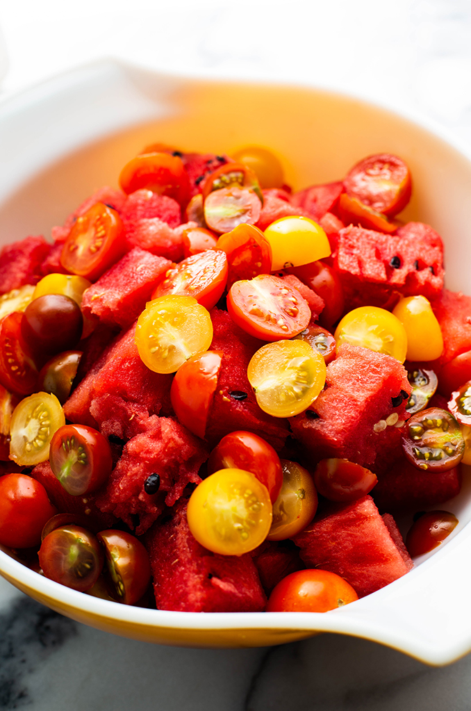 a bowl of watermelon and sliced tomatoes